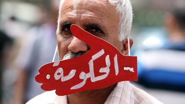 مرد عراقی در تظاهراتی در اعتراض به بیکاری در این کشور به صورت نمادین ماسک "حکومت" را به چهره دارد