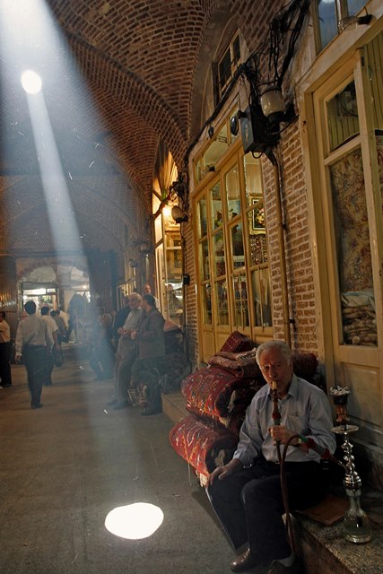 یکی از تیمچه های بازار فرش تبریز در ساعات نیمه روز بعد از صرف ناهار:  بازاریان طبق عادت قلیان چاق می کنند و ستون های نور بر آنها عمود می شود - عکس از شرق پارسی – عکاس بهار اصلانی