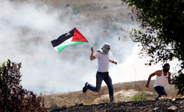 معترض فلسطینی پس از شلیک گاز اشک آور از سوی سربازان اسراییلی از محل تظاهرات در کرانه غربی می گریزد – 16 ژوییه 2014 - رویترز