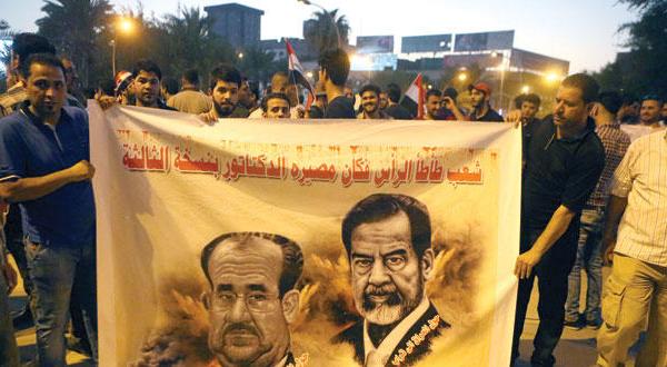 تظاهر کنندگان در حال حمل پلاکاردی با تصویر صدام حسین رئیس جمهور پیشین عراق و نوری المالکی نخست وزیر سابق در میدان تحریر در بغداد – عکس از آسوشیتد پرس