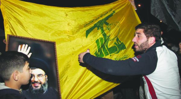 حامیان حزب الله در حال بر افراشتن پرچم ها و عکس های حسن نصرالله در انتظار مبارزان بازگشته از شهرک های الفوعه و کفریا که با یک هواپیمای ترکیه به بیروت بازگشتند – عکس از خبرگزاری فرانسه